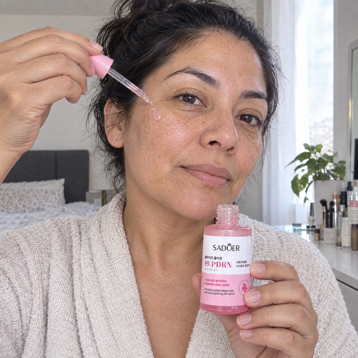 Mujer aplicando una gota de serum rosado de PDRN en el pomulo con el gotero
